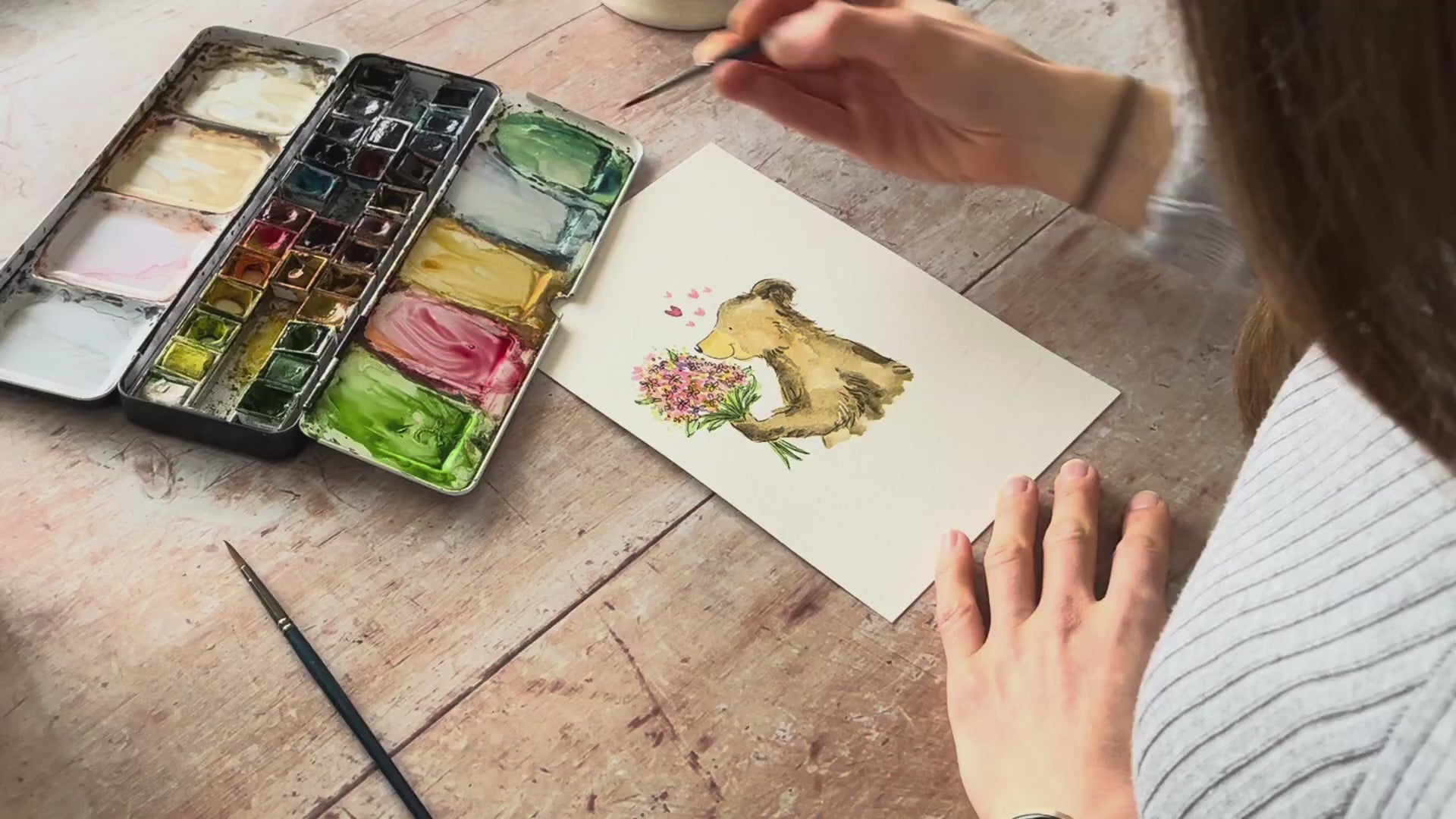 Ellie painting the bear holding a bunch of flowers from over her shoulder